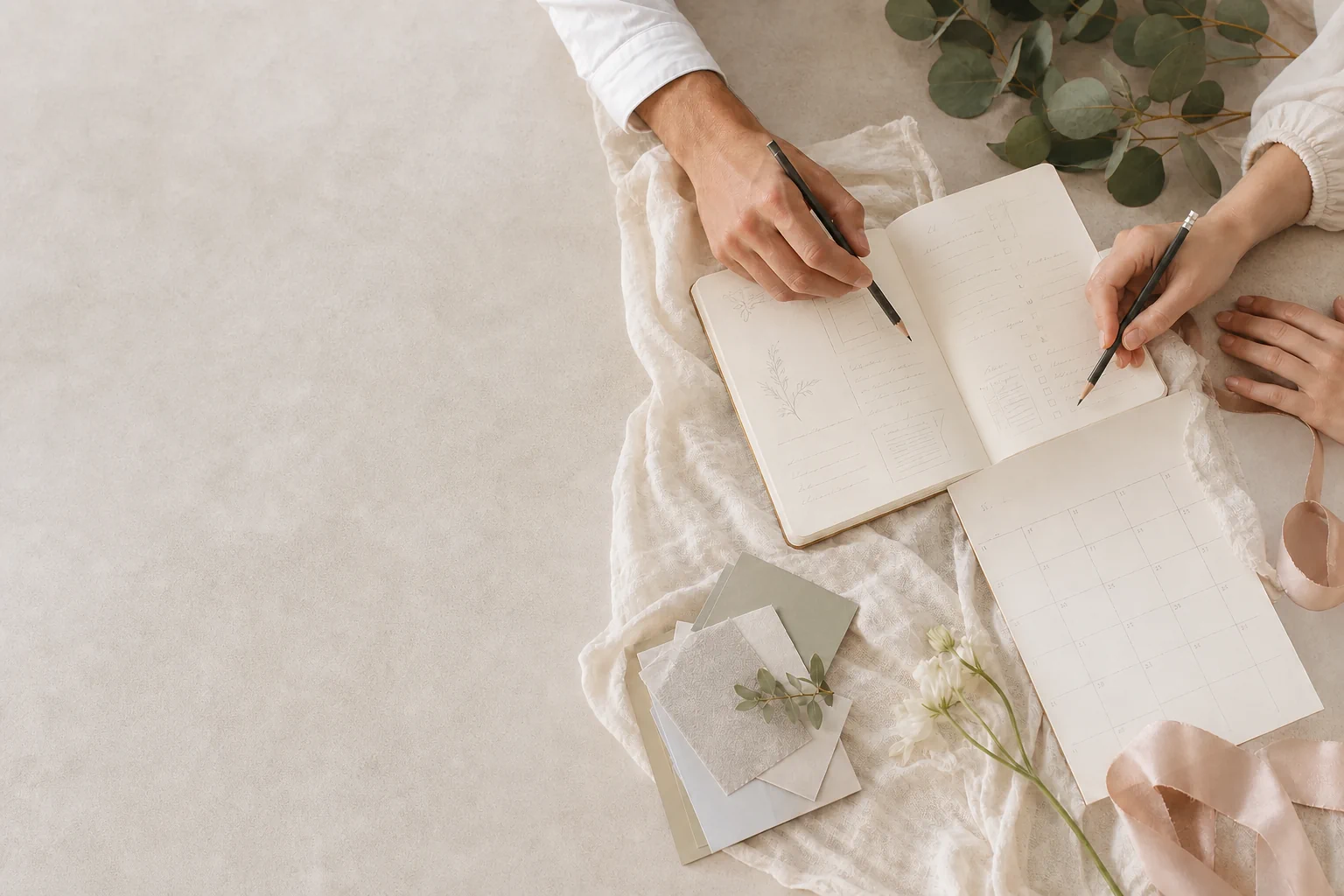 Two people planning together with a notebook, calendar and fabric samples
